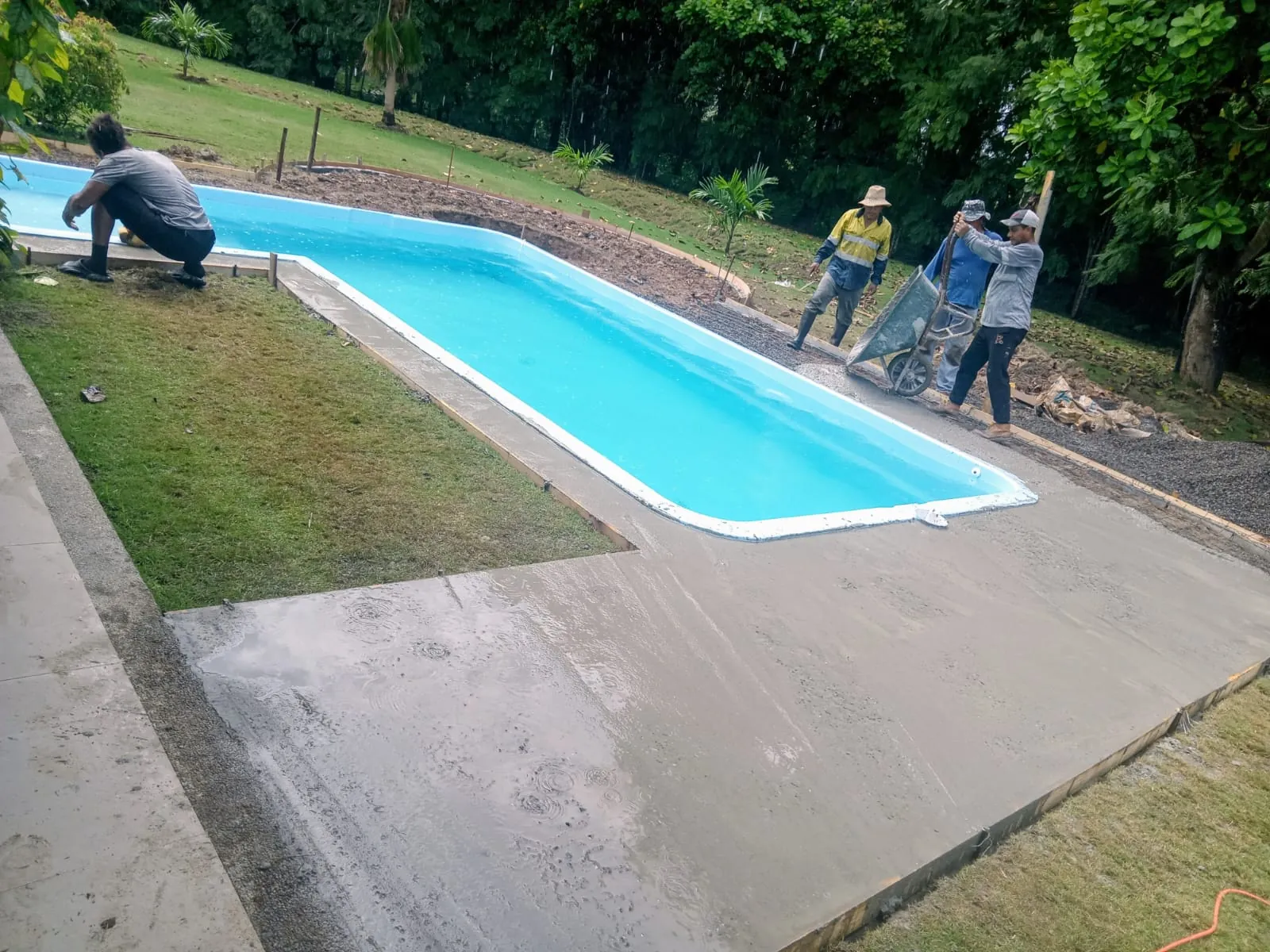 Instalación de piscina de fibra alargada con trabajadores