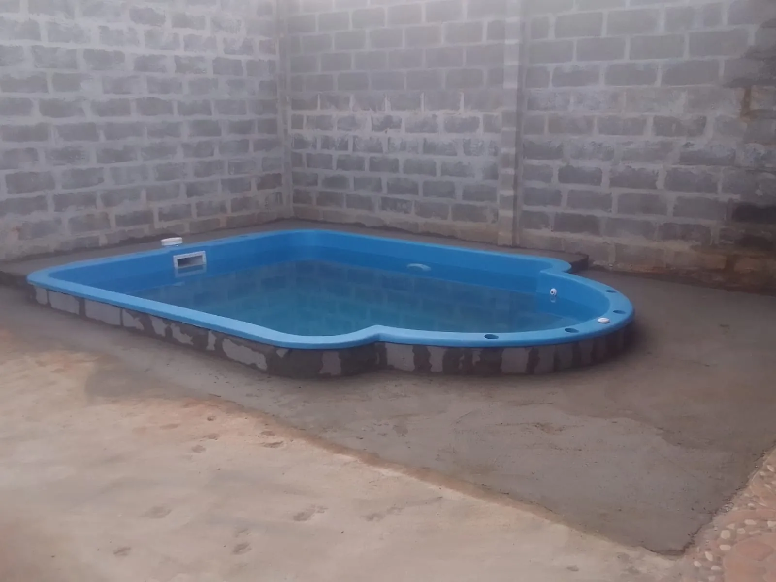 Piscina de fibra recién instalada con piso de concreto