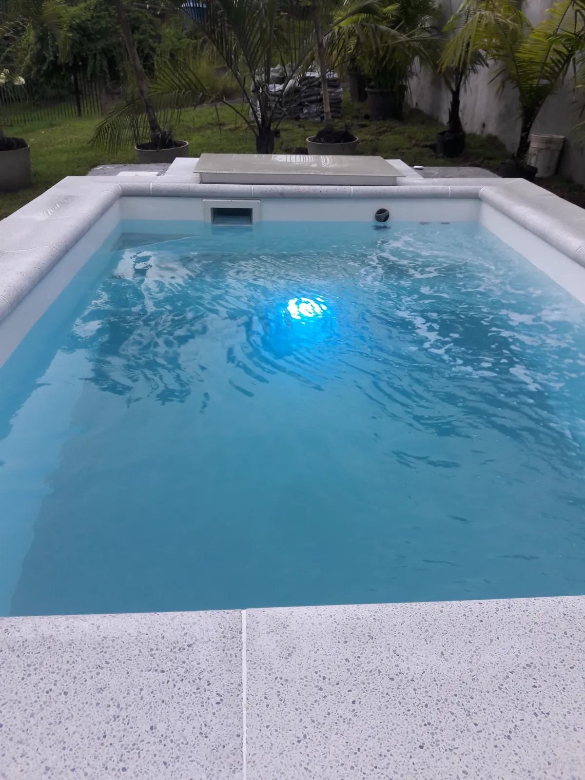 Piscina pequeña de fibra con iluminación subacuática y jardín