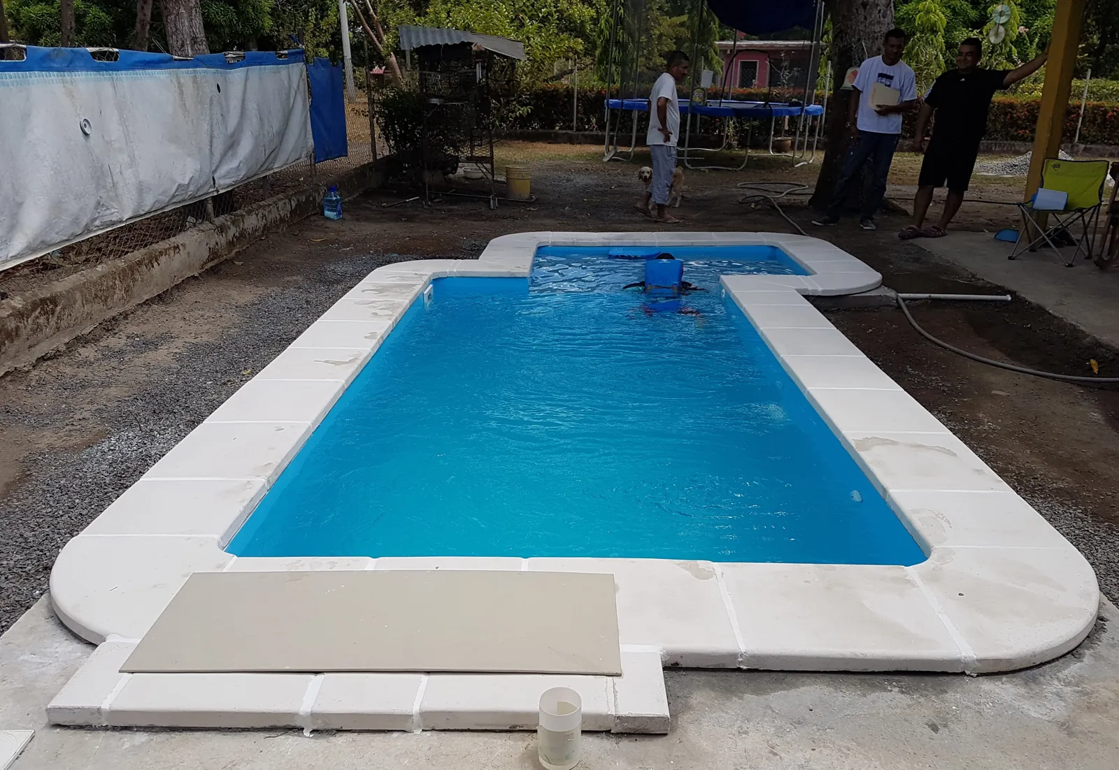 Piscina de fibra rectangular recién instalada con borde de piedra blanca