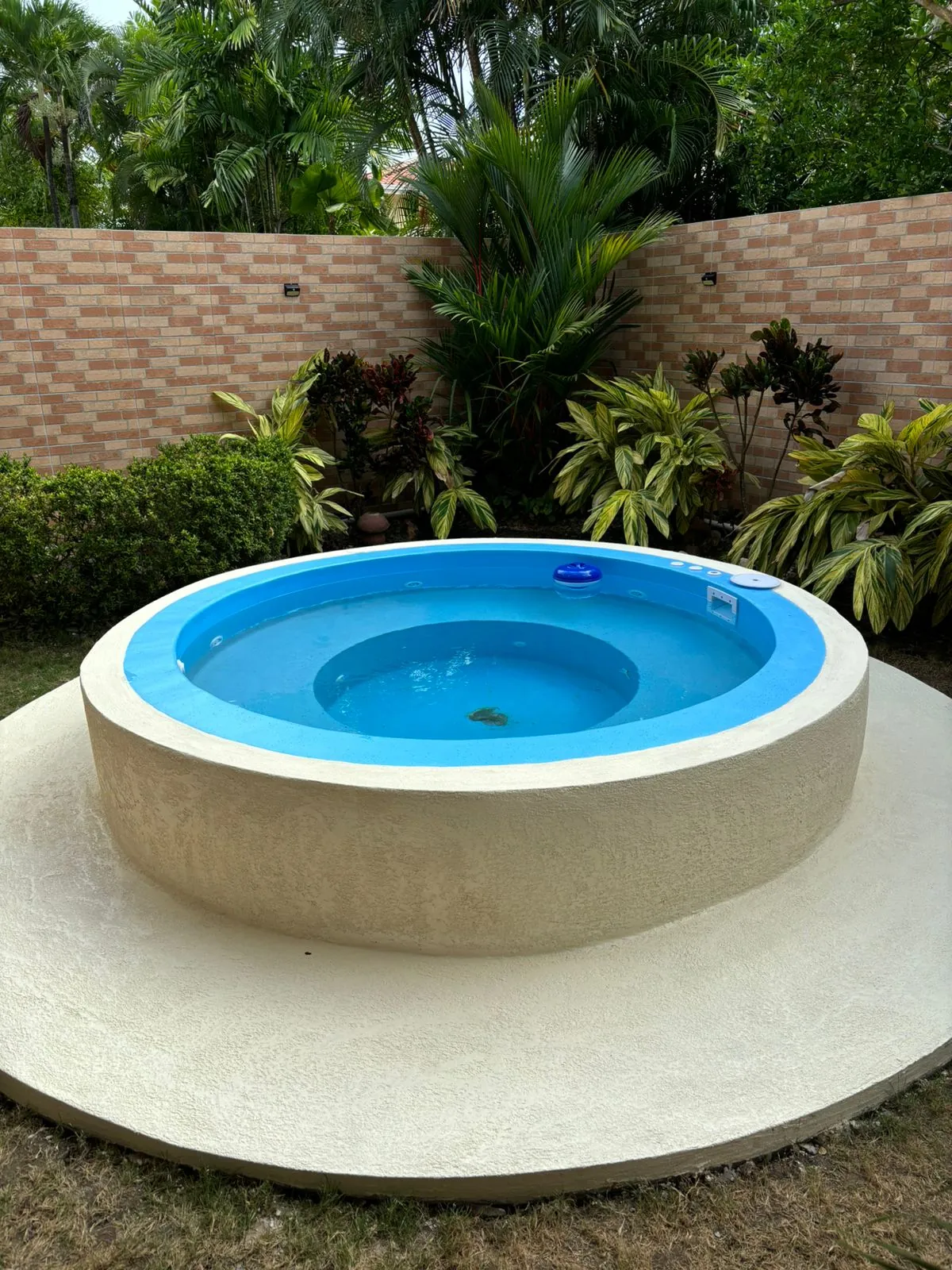 Jacuzzi redondo de fibra terminado con acabado beige en jardín de Panamá