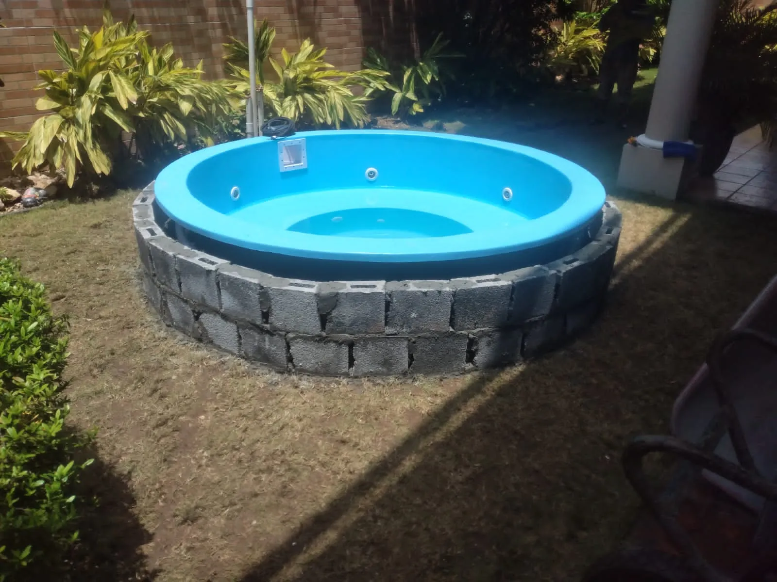 Jacuzzi redondo de fibra de vidrio junto a muro de piedra