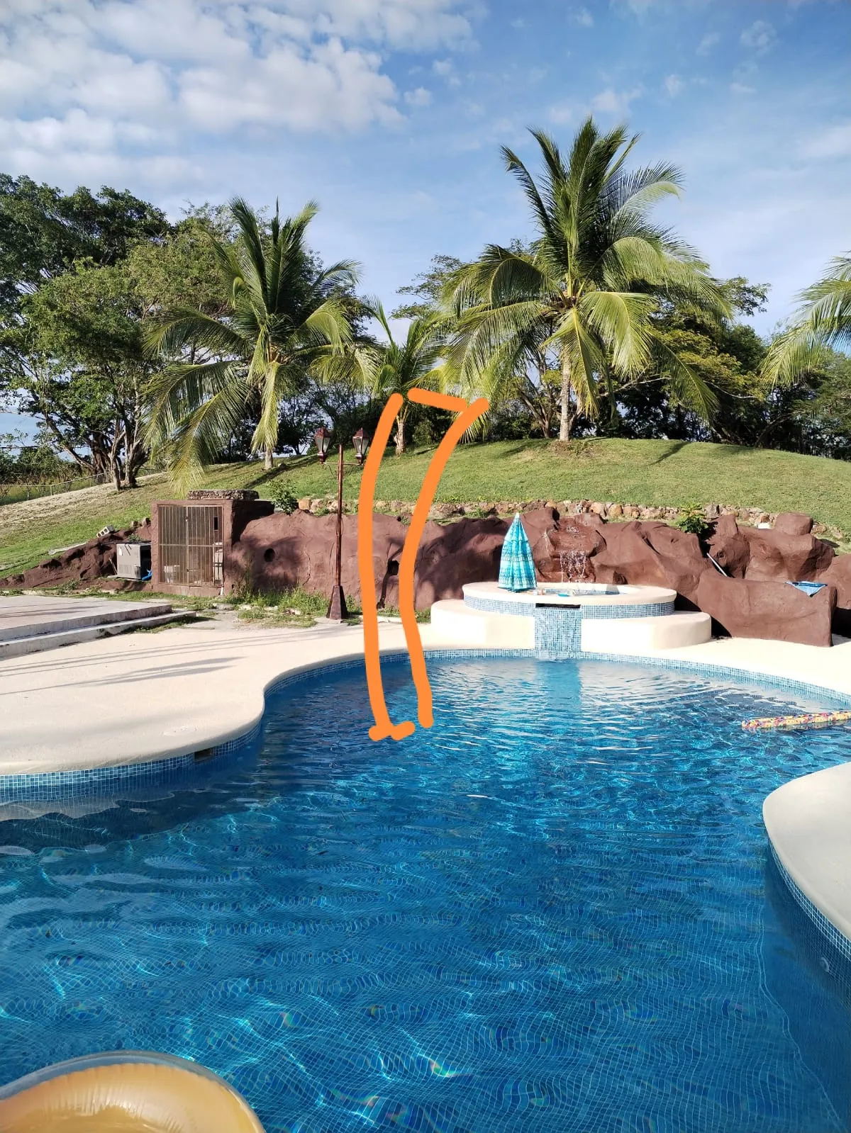Tobogán de fibra de vidrio naranja junto a la piscina