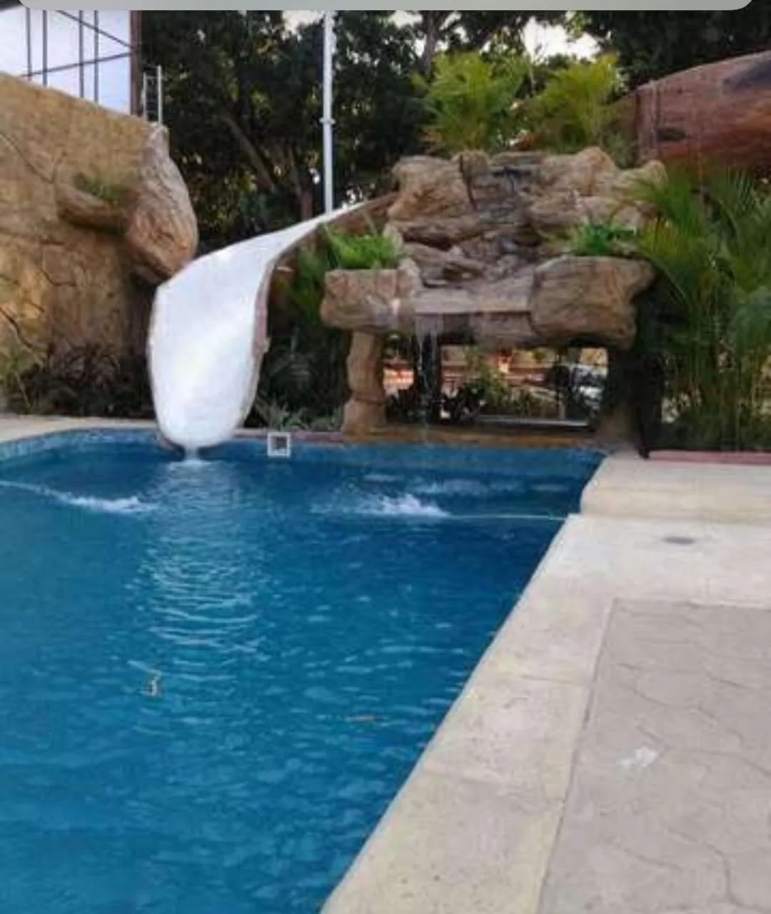 Tobogán de fibra de vidrio blanco con cascada de roca