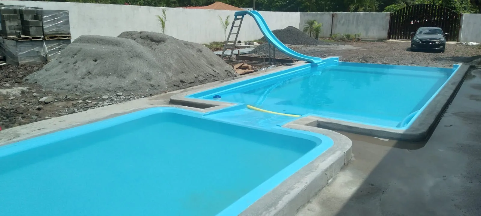 Dos piscinas de fibra con tobogán en instalación